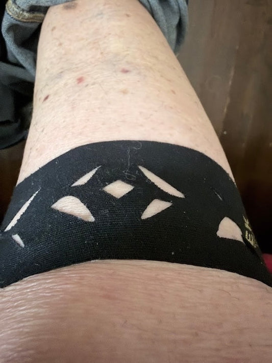 Verified buyer photo: a black pre-cut Easy Tape kinesiology strip with diamond cut-outs worn across an older adult's knee